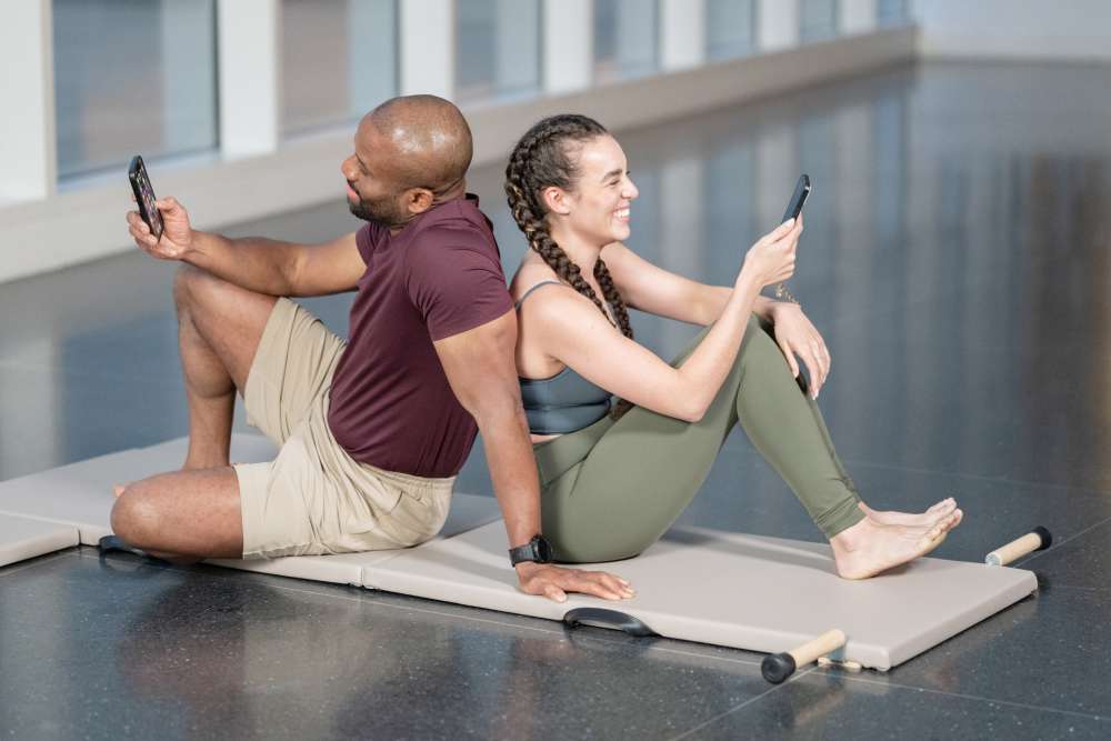 two people on a folding mat on their phones