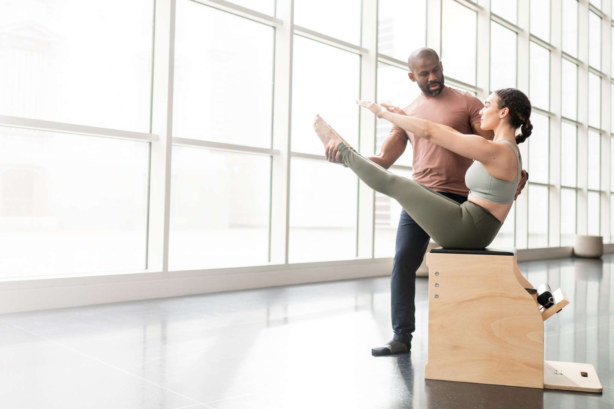 pilates instructor assisting student on Wunda Chair